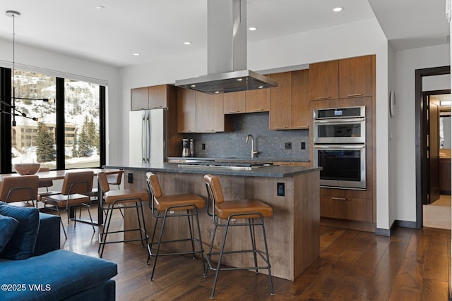 kitchen with decorative backsplash, dark wood-style floors, stainless steel appliances, and island range hood