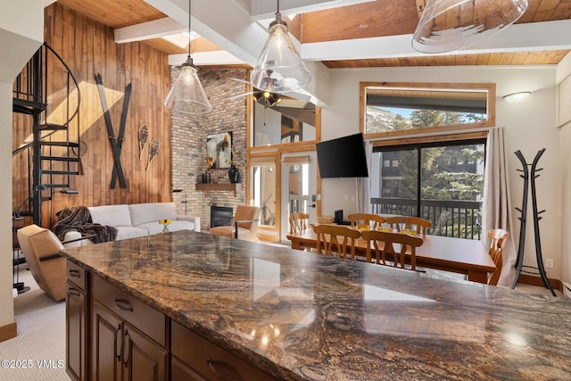 kitchen featuring a fireplace, beam ceiling, wooden walls, and wood ceiling