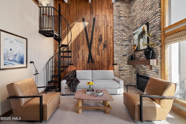 living area with a large fireplace, wooden walls, and a towering ceiling