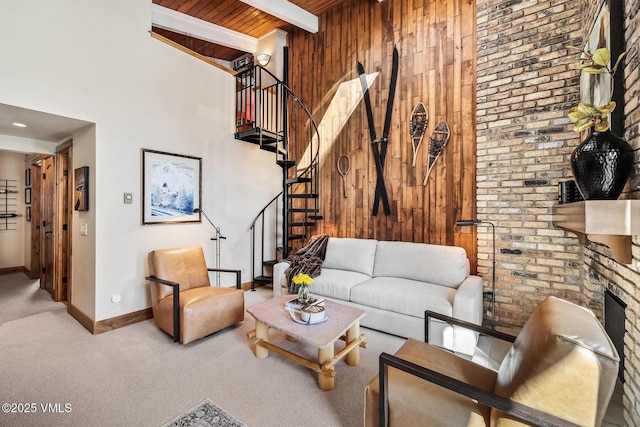 living room featuring beam ceiling, carpet, wood walls, and a towering ceiling