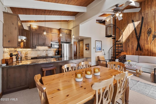 dining area with stairs, beam ceiling, wood walls, and light carpet