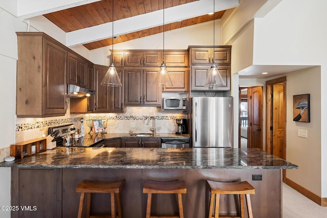 kitchen with a peninsula, vaulted ceiling with beams, stainless steel appliances, under cabinet range hood, and tasteful backsplash