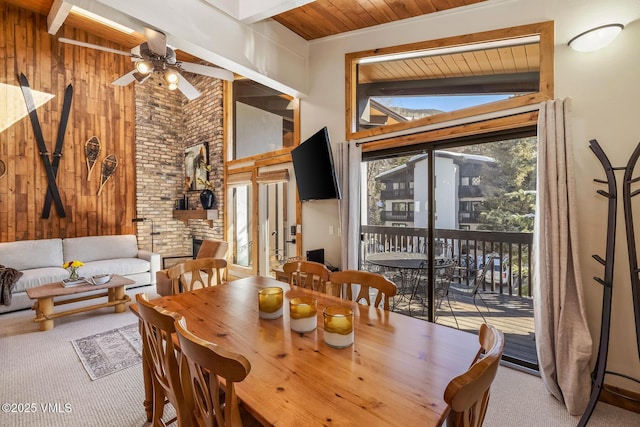 carpeted dining space featuring beamed ceiling, wood walls, and wooden ceiling