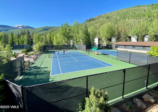 view of sport court with a mountain view, fence, and a forest view