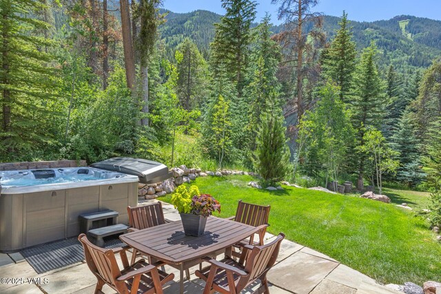 4916 Juniper Ln, Vail, CO 81657 - view of patio / terrace featuring a wooded view, a hot tub, outdoor dining space, and a mountain view