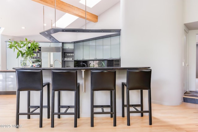 4916 Juniper Ln, Vail, CO 81657 - kitchen featuring paneled fridge, dark countertops, a skylight, a breakfast bar area, and high vaulted ceiling
