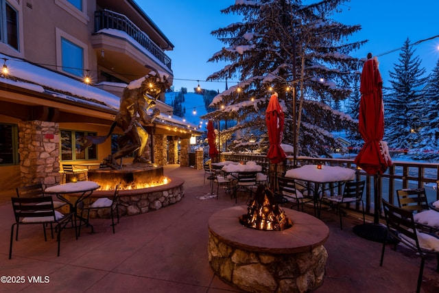 patio terrace at dusk featuring a balcony and an outdoor fire pit