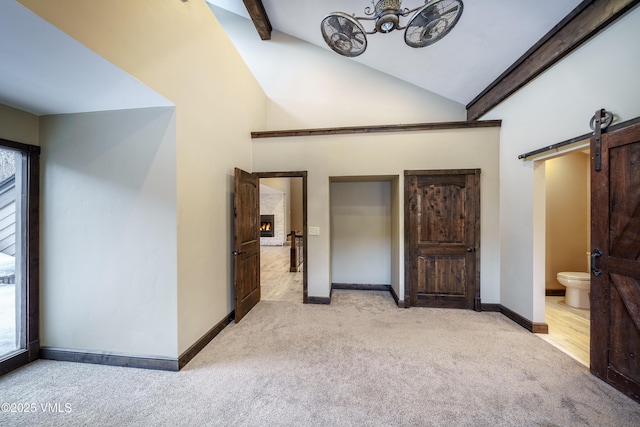 interior space featuring light carpet, high vaulted ceiling, a barn door, and beamed ceiling