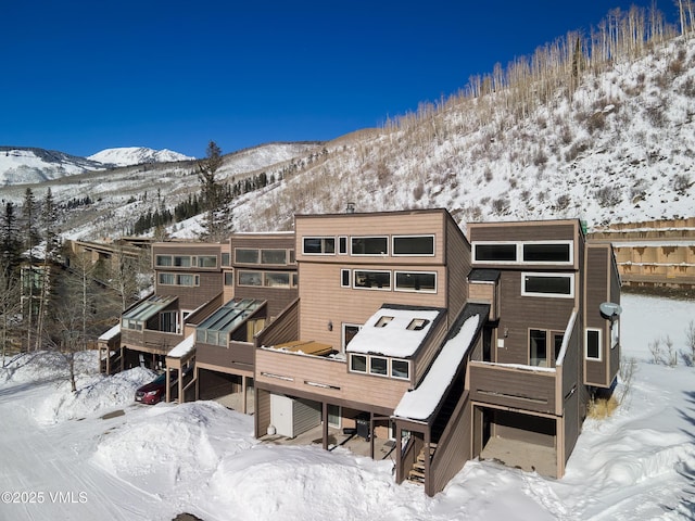 snow covered house with a deck with mountain view