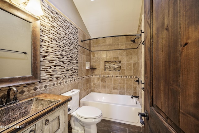 full bathroom with tile walls, decorative backsplash, vaulted ceiling, toilet, and tiled shower / bath