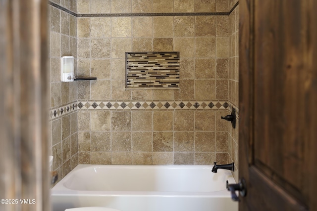 bathroom with tiled shower / bath combo and toilet