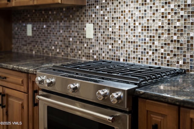 details with tasteful backsplash, dark stone counters, and stainless steel range with gas stovetop