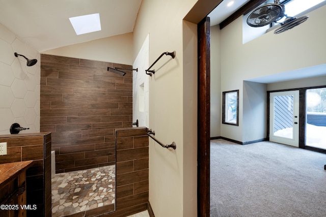 bathroom with a tile shower, high vaulted ceiling, and a skylight