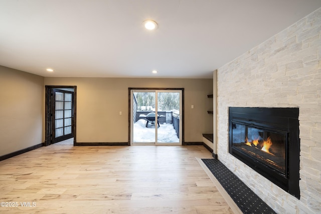 unfurnished living room with a stone fireplace and light hardwood / wood-style flooring