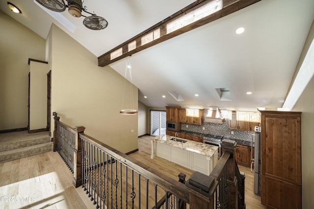 stairway with lofted ceiling with beams, sink, and hardwood / wood-style floors