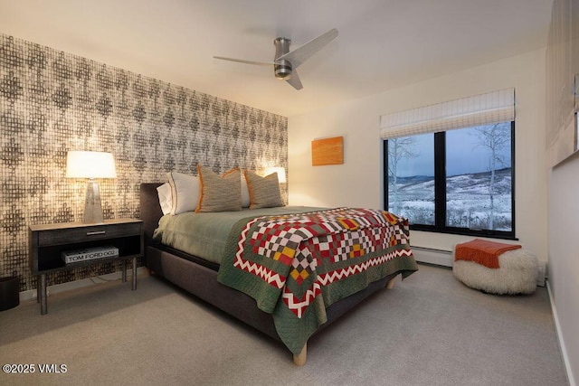 carpeted bedroom with an accent wall, a baseboard radiator, and a ceiling fan