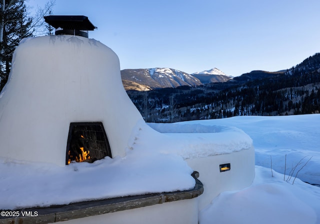 exterior space with a lit fireplace and a mountain view