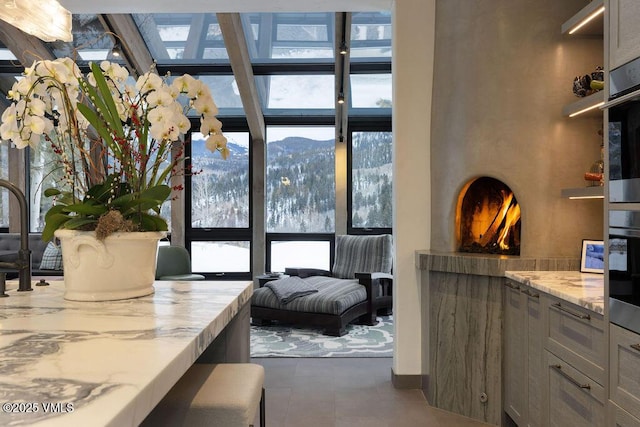 interior space featuring a warm lit fireplace and a wall of windows