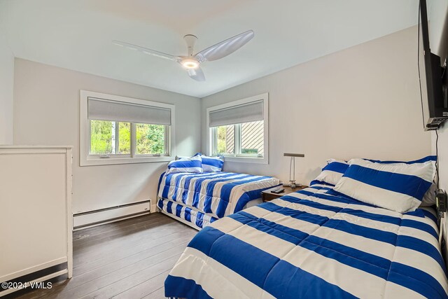 bedroom featuring ceiling fan, a baseboard heating unit, and dark hardwood / wood-style floors