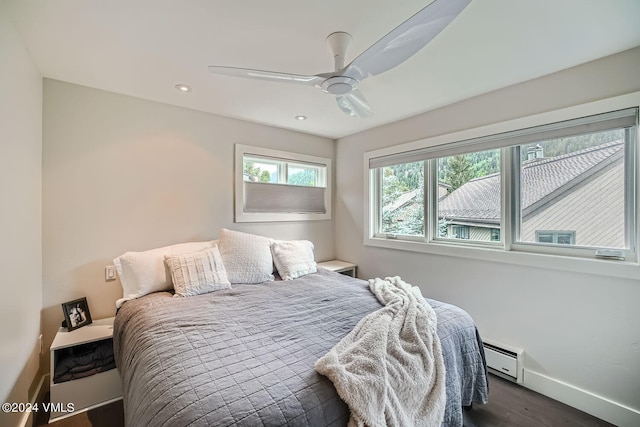 bedroom with a baseboard heating unit, dark hardwood / wood-style floors, and ceiling fan