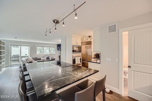 kitchen with a center island, white cabinets, a kitchen breakfast bar, and black appliances