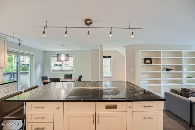 kitchen featuring pendant lighting, white cabinetry, dark stone countertops, a center island, and black electric cooktop