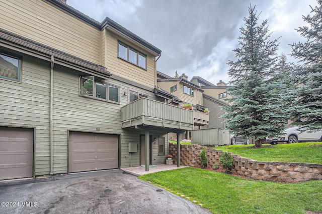 exterior space with a balcony, a garage, and a lawn