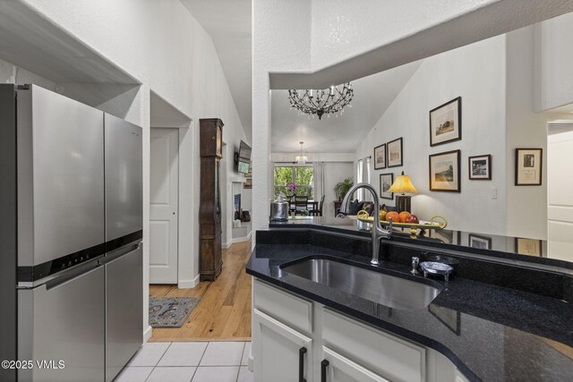 55 River Pines Ct Unit A302, Edwards, CO 81632 - kitchen featuring freestanding refrigerator, a sink, a chandelier, vaulted ceiling, and white cabinetry