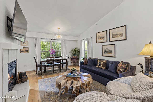 55 River Pines Ct Unit A302, Edwards, CO 81632 - living room featuring lofted ceiling, hardwood / wood-style floors, a glass covered fireplace, baseboards, and a chandelier