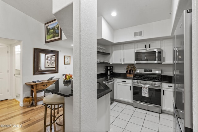 55 River Pines Ct Unit A302, Edwards, CO 81632 - kitchen with stainless steel appliances, dark countertops, open shelves, a kitchen bar, and a peninsula