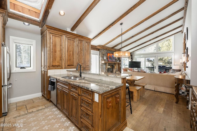 kitchen featuring sink, hanging light fixtures, dark stone countertops, appliances with stainless steel finishes, and kitchen peninsula