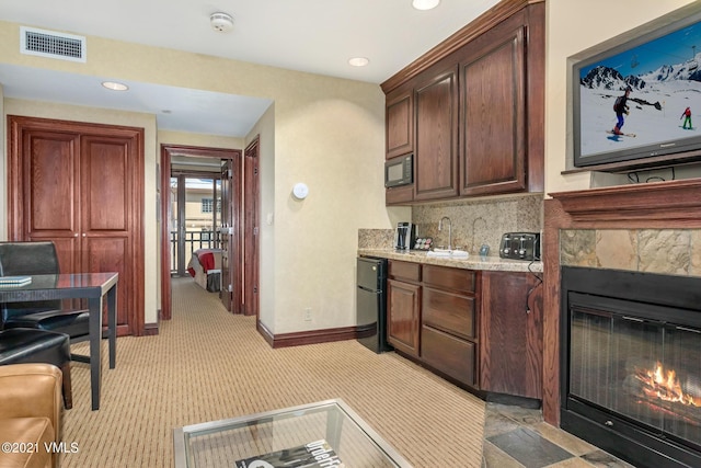 kitchen with visible vents, baseboards, decorative backsplash, black appliances, and a tiled fireplace