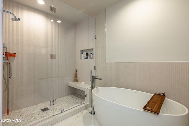 bathroom with a soaking tub, marble finish floor, and a stall shower