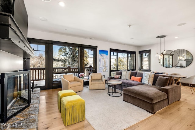 living area with a stone fireplace, recessed lighting, and light wood-type flooring