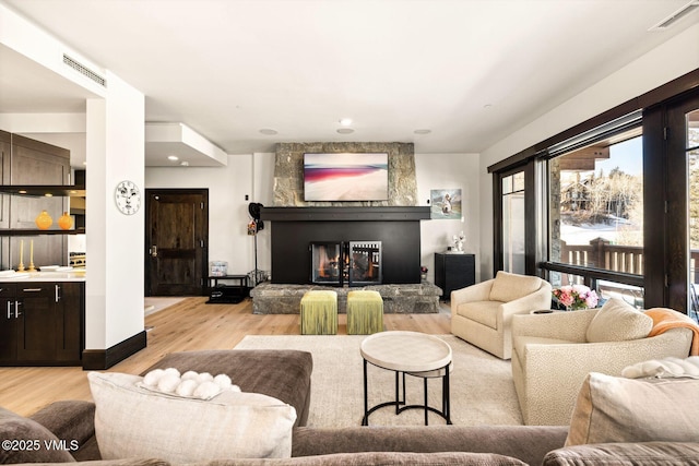 living area featuring visible vents, light wood-style flooring, and a fireplace