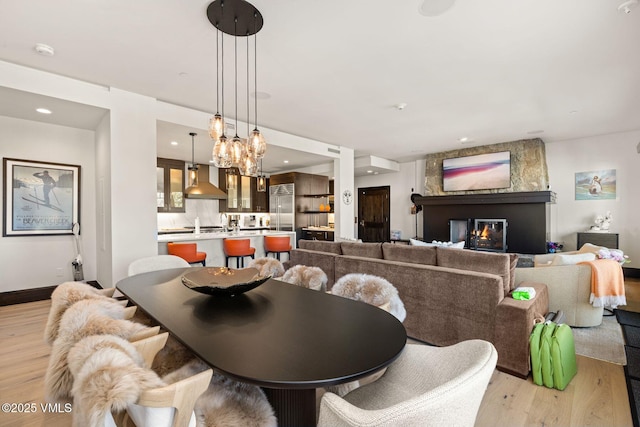 dining area featuring baseboards, light wood finished floors, a fireplace, recessed lighting, and a notable chandelier