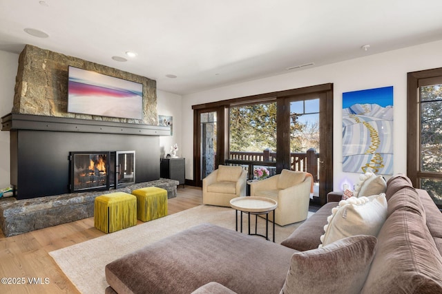 living room featuring wood finished floors, visible vents, and a large fireplace