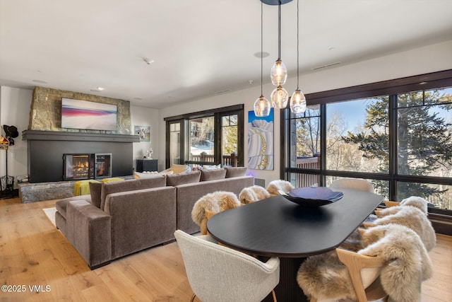 dining area with a fireplace, visible vents, and light wood finished floors