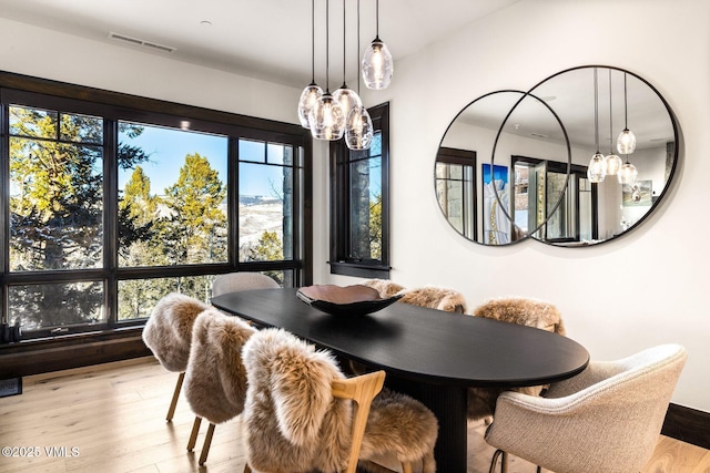 dining room with a chandelier, visible vents, and wood finished floors