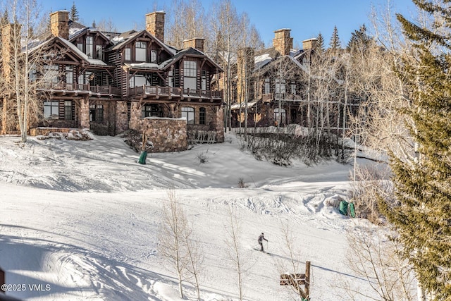 snow covered rear of property featuring a chimney