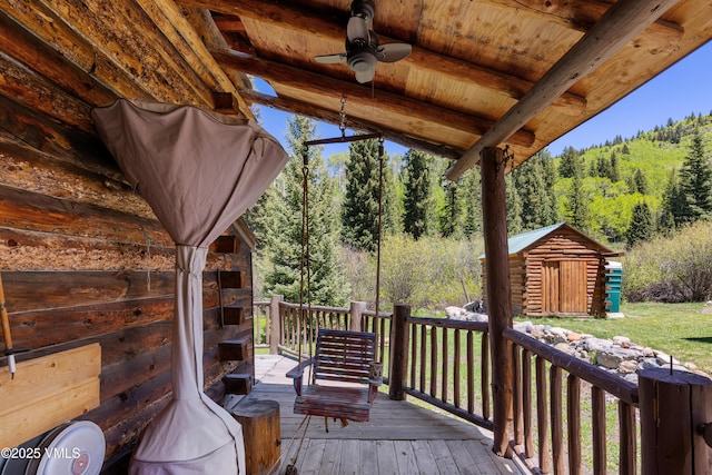 245 Main St, Eagle, CO 81631 - wooden terrace with a forest view, an outdoor stone fireplace, a storage unit, and a ceiling fan