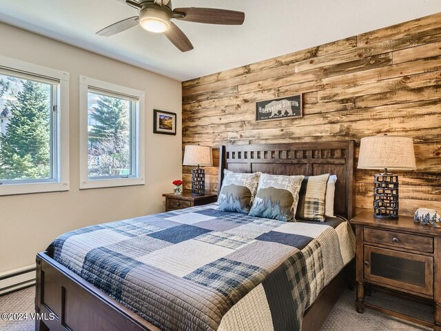 bedroom with ceiling fan, wooden walls, light colored carpet, and baseboard heating