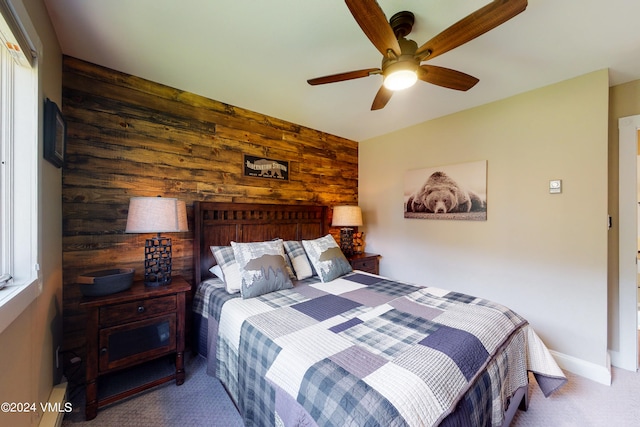 bedroom with ceiling fan, carpet flooring, and wooden walls