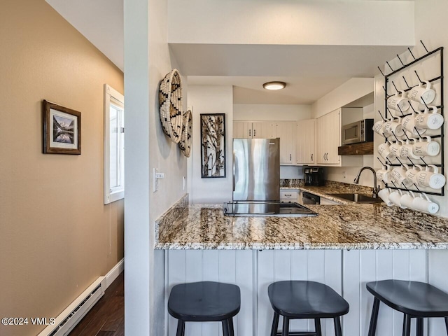 kitchen with appliances with stainless steel finishes, a baseboard radiator, sink, light stone counters, and kitchen peninsula