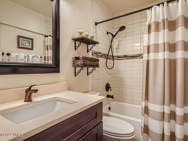 full bathroom with vanity, shower / tub combo with curtain, and toilet