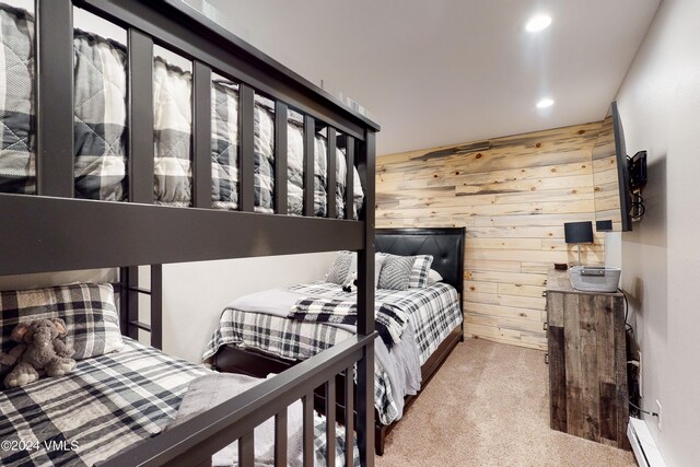 carpeted bedroom featuring baseboard heating and wood walls