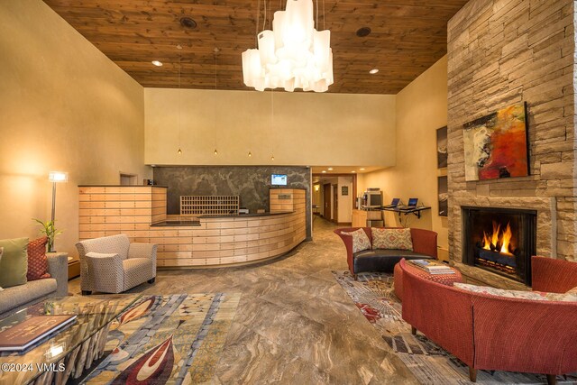 welcome area featuring a stone fireplace and a notable chandelier