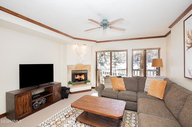 carpeted living room with a premium fireplace, crown molding, and ceiling fan