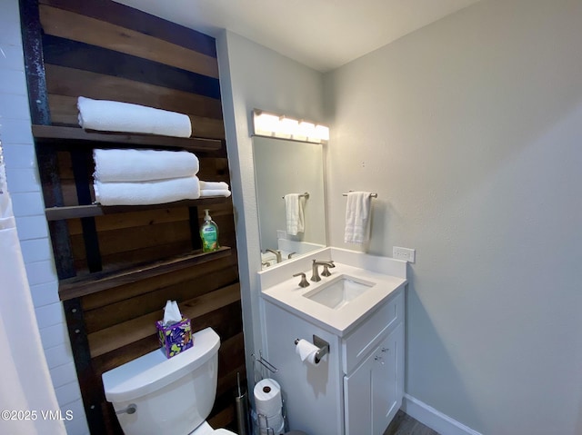half bath featuring vanity, baseboards, and toilet