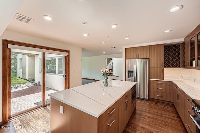 482 Charolais Cir, Edwards, CO 81632 - kitchen featuring stainless steel fridge, dark wood-type flooring, light stone countertops, glass insert cabinets, and a center island